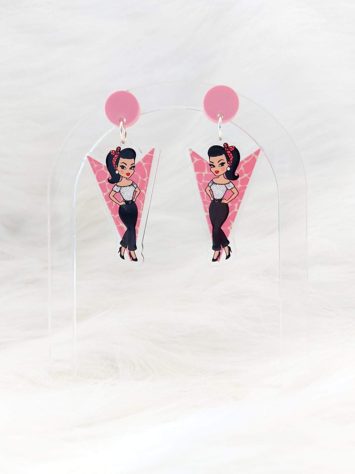 Pair of lightweight acrylic earrings in the shape of a pink downward pointing arrow with a retro-style illustrated girl, pink circular stud at the top, stainless steel posts and large backs, designed and handmade in Australia