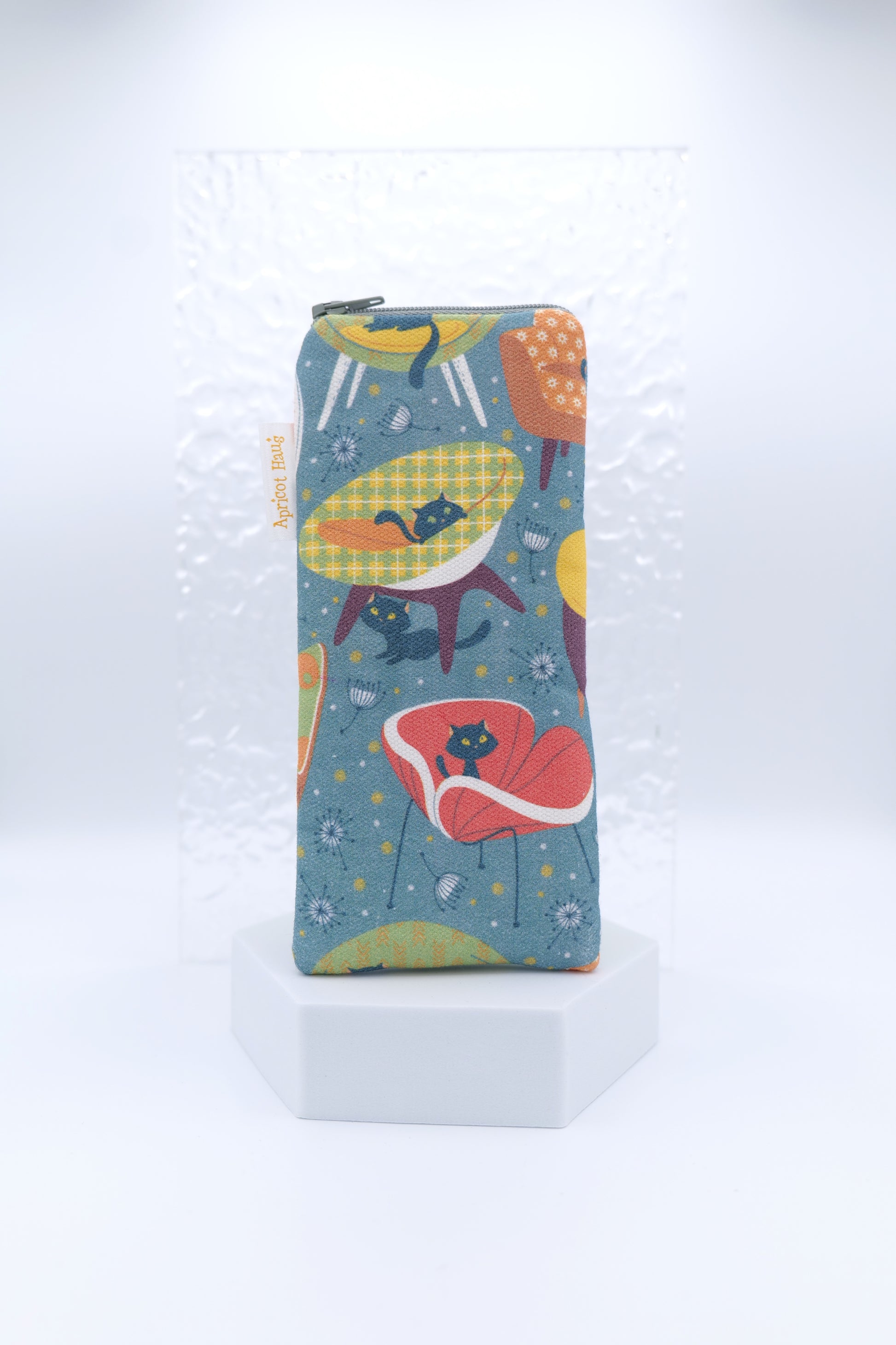 Glasses case featuring the 60s Cats and Chairs design, with stylised black cats sitting on retro-style chairs in red, yellow and green on a dark background; handmade in Melbourne from cotton canvas with a zip top