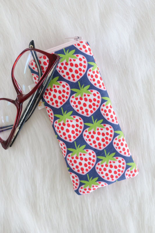 Blue strawberry patterned glasses case made from cotton canvas with zip top closure, padded and lined with soft cotton, displayed on a white background alongside a pair of eyeglasses. Handmade in Melbourne and certified Australian Made.