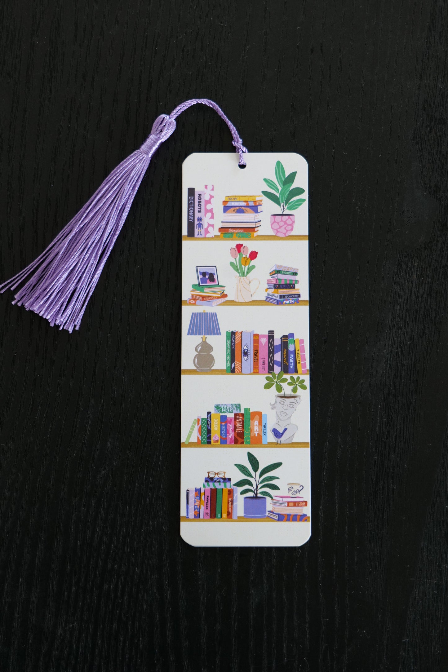 Bookmark featuring five shelves, each with books, lamps, plants and a purple tassel, sitting against a black backdrop