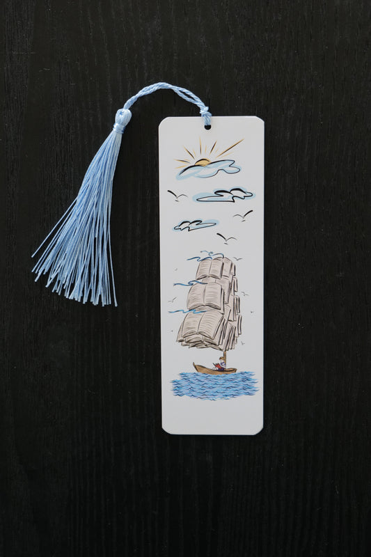 Bookmark featuring an old-fashioned ship with large sails made out of book pages, with clouds and sun and a light blue tassel, sitting against a black backdrop