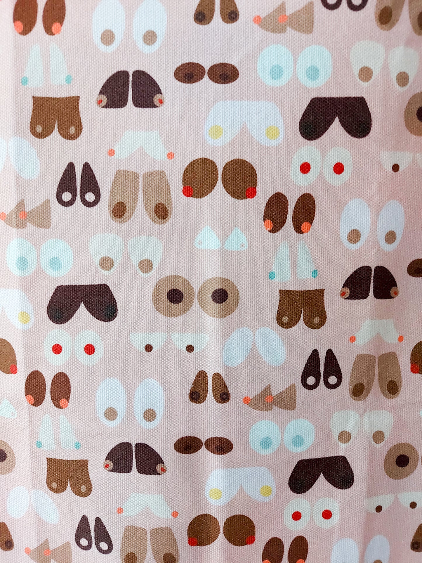 Close up of Breasts tea towel design,  multiple illustrations of breast shapes and colours against a pale pink background
