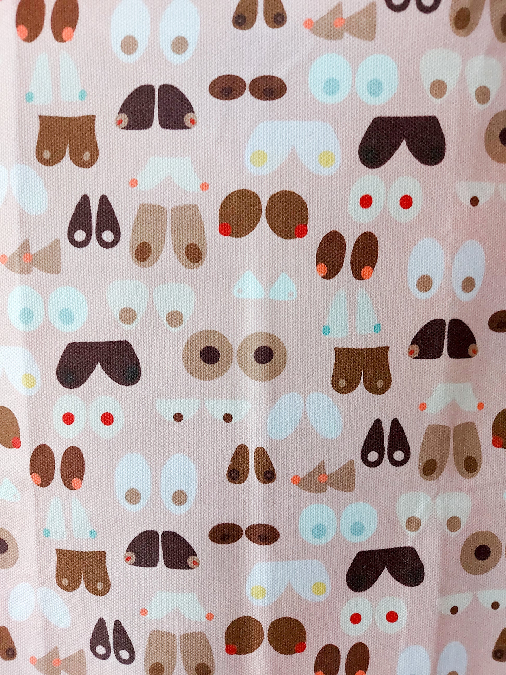 Close up of Breasts tea towel design,  multiple illustrations of breast shapes and colours against a pale pink background
