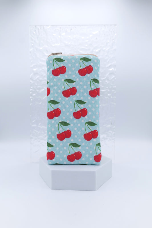 Glasses case with Cherries on Blue design featuring bright red cherries with green stems on a soft blue background with white polka dots; made from cotton canvas with zip top closure, padded and lined with soft cotton, handmade in Melbourne and certified Australian Made; pattern placement may vary slightly and individual items may have small quirks due to the handmade nature of the product.