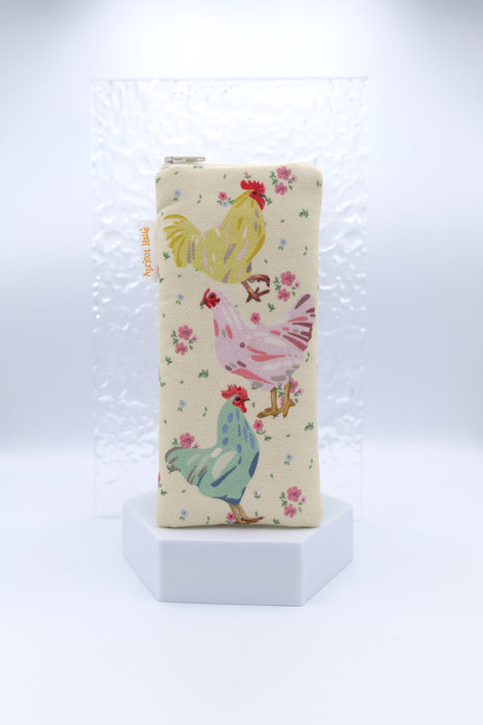 Glasses case featuring Chooks design with three colourful chickens stacked vertically — yellow, pink, and teal — surrounded by small pink florals on a cream background; made from cotton canvas with a zip-top closure, padded and lined to protect lenses, handmade in Melbourne and certified Australian Made; matching apron and tea towel available; pattern placement may vary slightly due to the handmade nature of the product.
