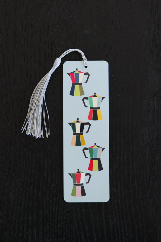 Bookmark featuring five brightly coloured coffee pots on a pale blue background with an ice blue tassel, sitting against a black backdrop