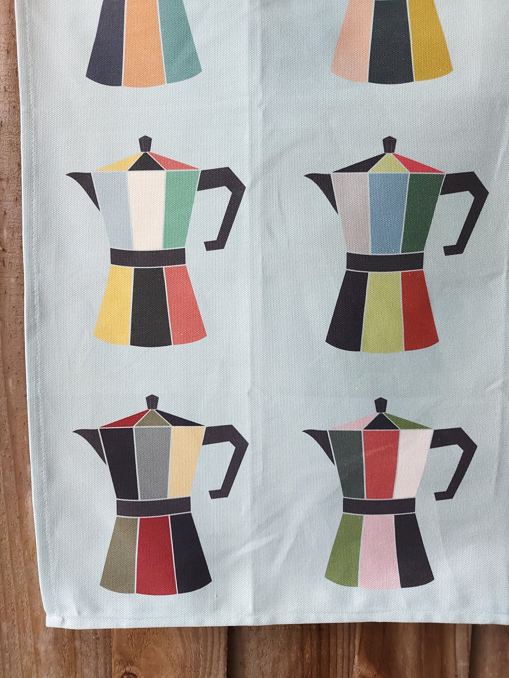 Close up of Coffee Pot tea towel showing four colourful moka pots on a light blue background