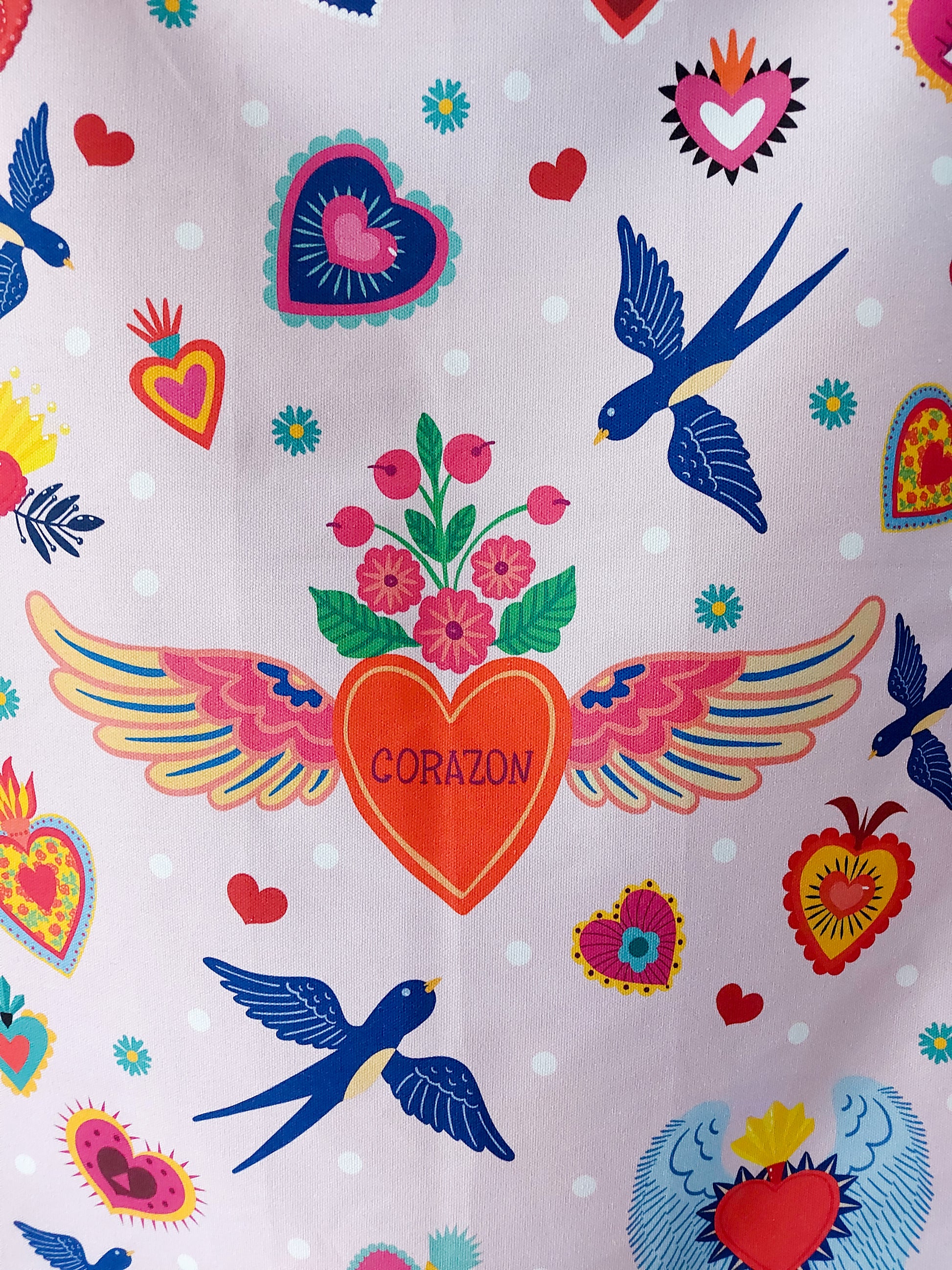 Close up photo of the central heart of the Corazon tea towel, with some blue birds and other hearts and flowers