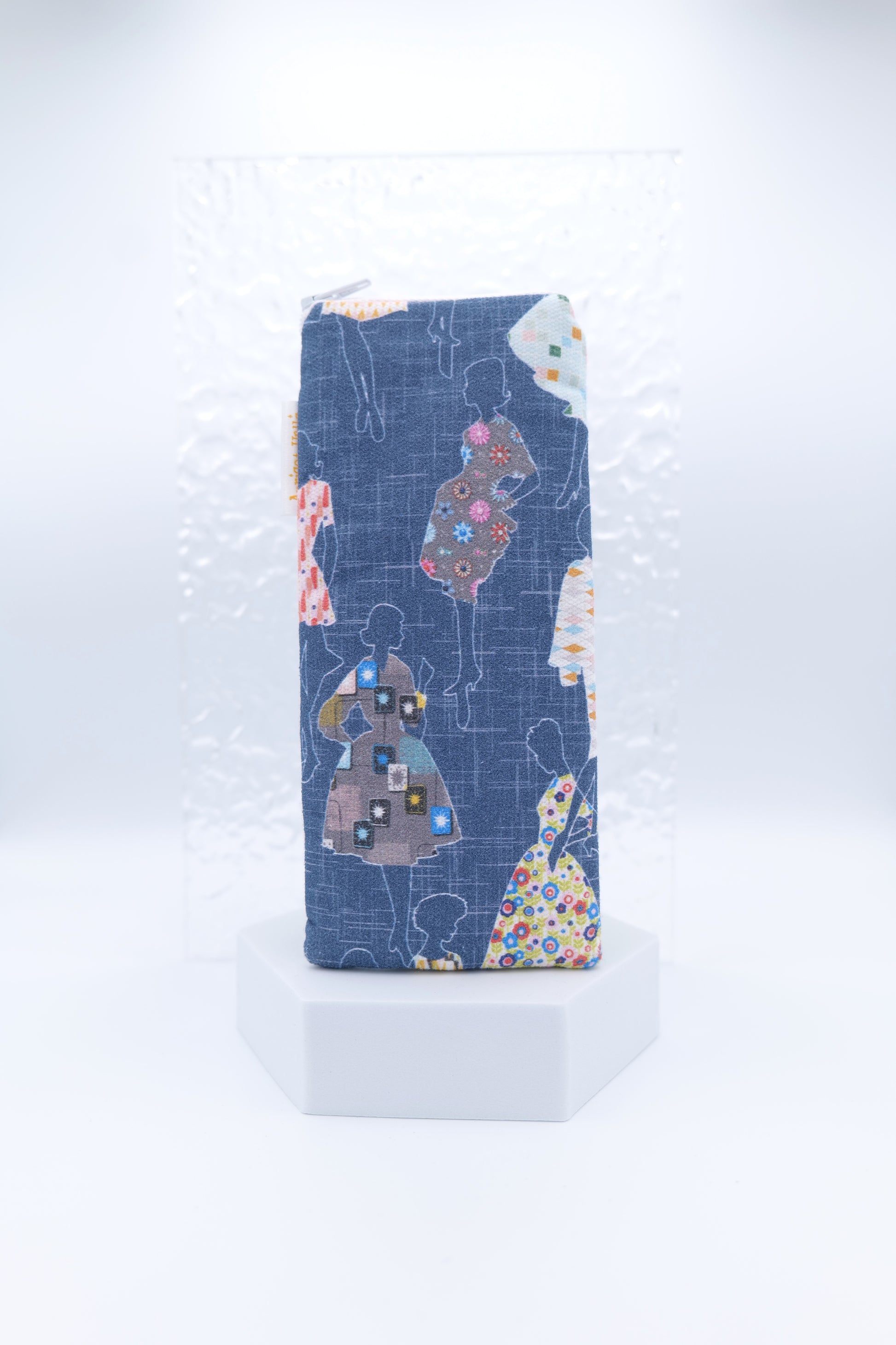Glasses case featuring the Dressmakers design with outlined women in 1950s-style dresses, each filled with a unique patterned print, set against a navy background; made from cotton canvas with a zip-top closure, padded and lined to protect lenses, handmade in Melbourne and certified Australian Made; pattern placement may vary slightly due to the handmade nature of the product.