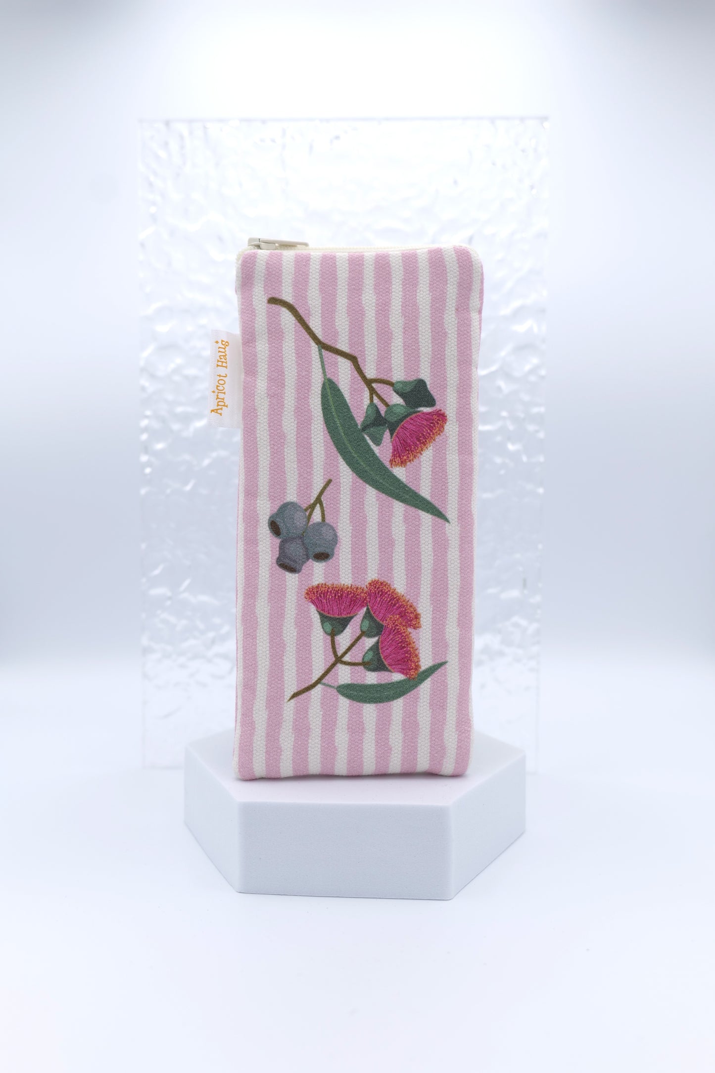 Glasses case with Eucalyptus design featuring eucalyptus blossoms and gumnuts on a pink striped background; made from cotton canvas with zip top closure, padded and lined with soft cotton, handmade in Melbourne and certified Australian Made; matching apron and tea towel available; pattern placement may vary slightly and individual items may have small quirks due to the handmade nature of the product.