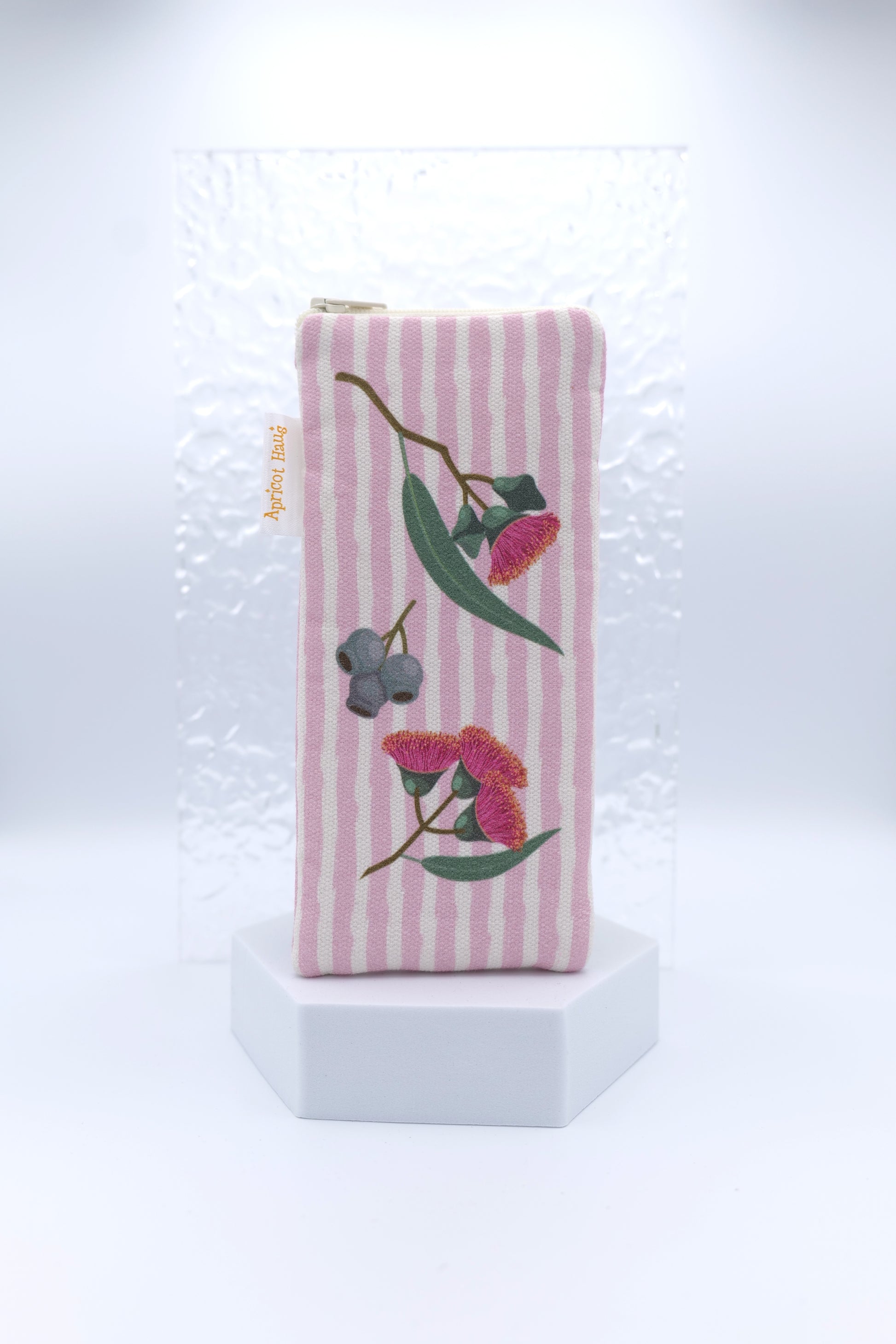 Glasses case with Eucalyptus design featuring eucalyptus blossoms and gumnuts on a pink striped background; made from cotton canvas with zip top closure, padded and lined with soft cotton, handmade in Melbourne and certified Australian Made; matching apron and tea towel available; pattern placement may vary slightly and individual items may have small quirks due to the handmade nature of the product.