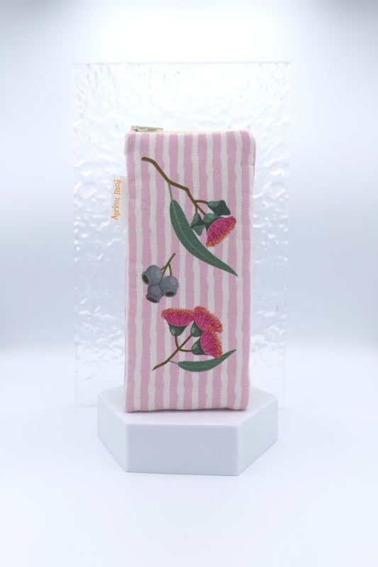 Glasses case with Eucalyptus design featuring eucalyptus blossoms and gumnuts on a pink striped background; made from cotton canvas with zip top closure, padded and lined with soft cotton, handmade in Melbourne and certified Australian Made; matching apron and tea towel available; pattern placement may vary slightly and individual items may have small quirks due to the handmade nature of the product.