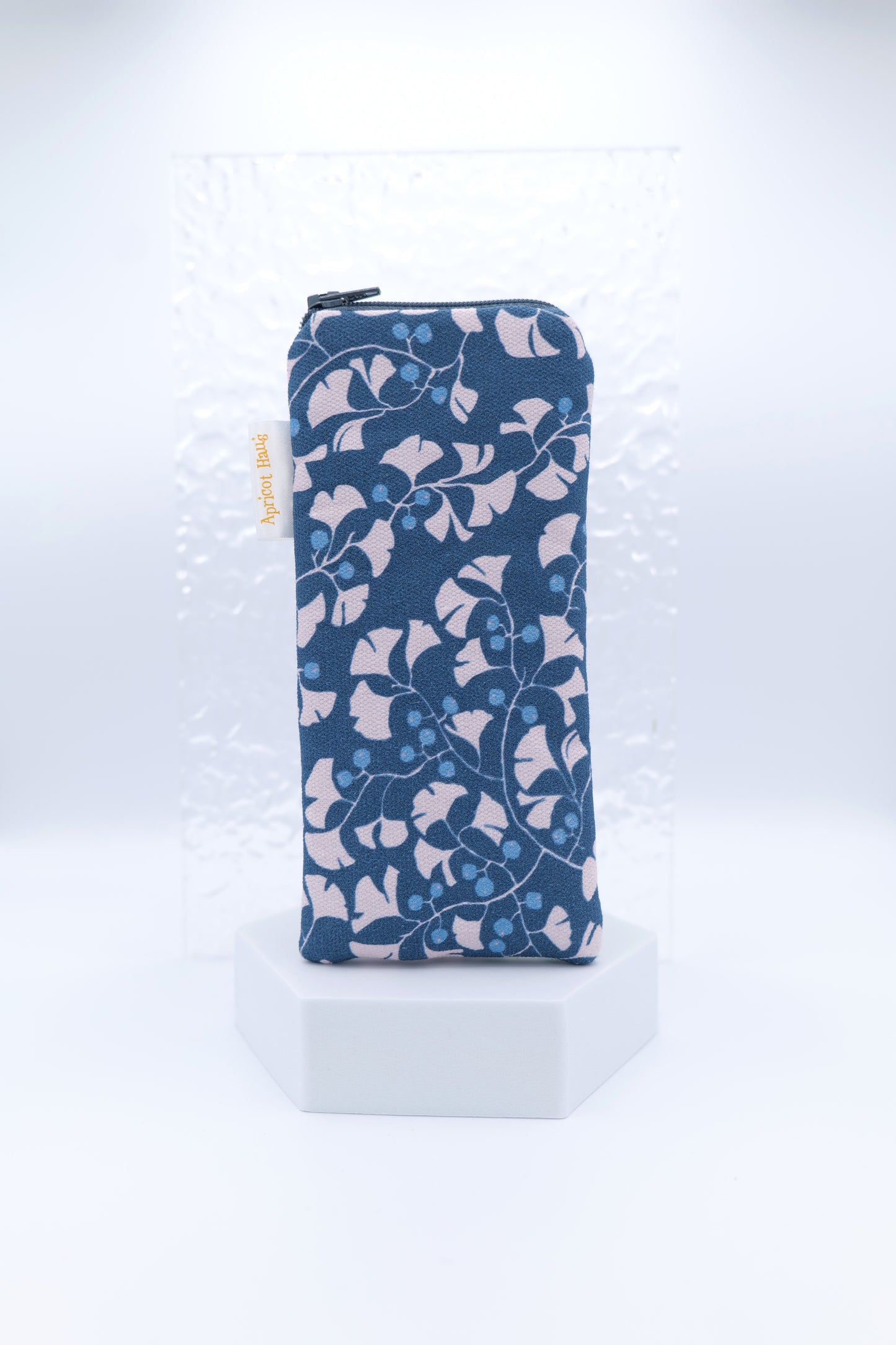 Glasses case featuring Gingko Leaves design with stylised pale gingko leaves arranged on a navy background with bright blue berries; made from cotton canvas with a zip‑top closure, padded and lined to protect lenses, handmade in Melbourne and certified Australian Made; pattern placement may vary slightly due to the handmade nature of the product.