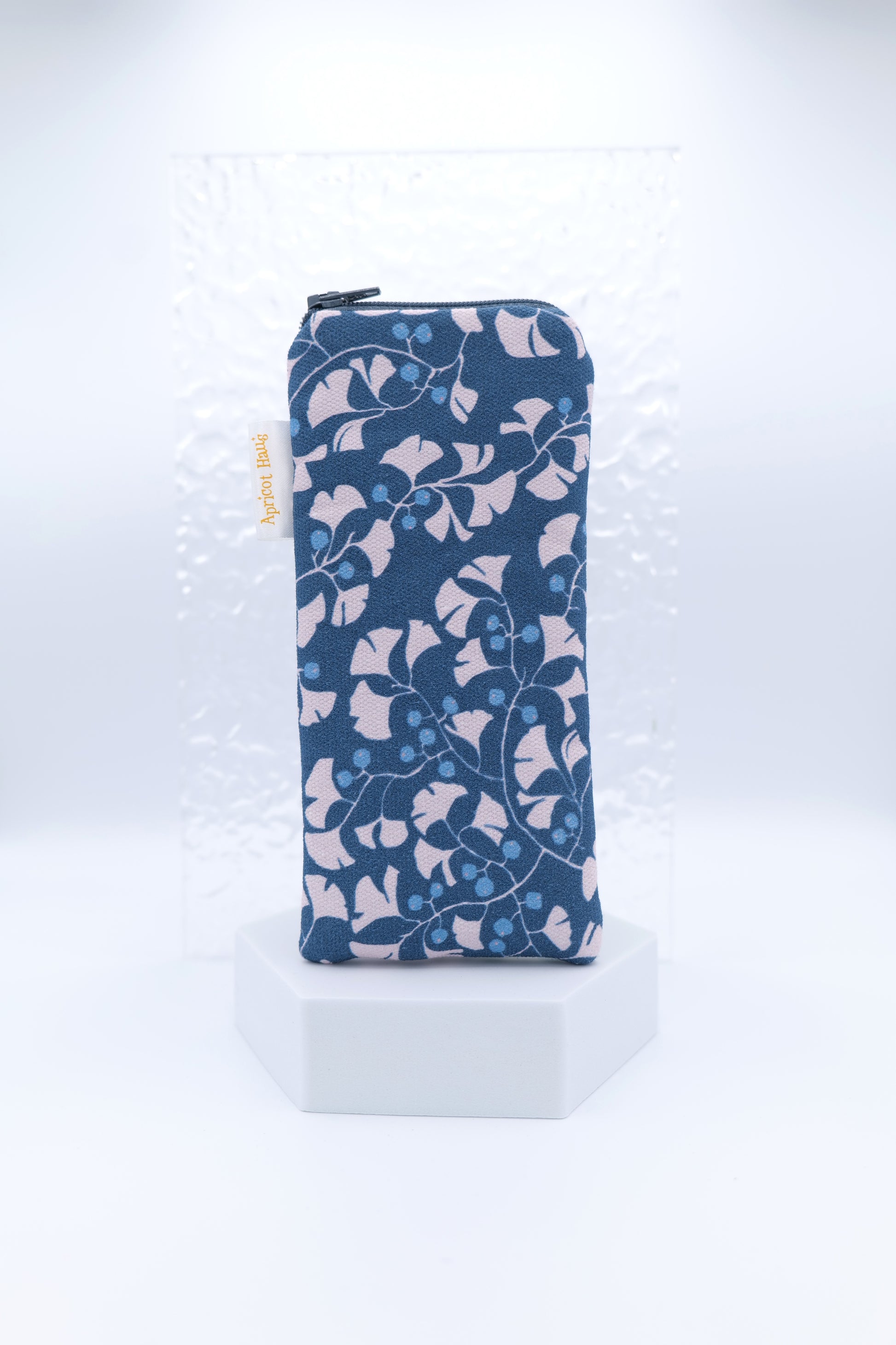 Glasses case featuring Gingko Leaves design with stylised pale gingko leaves arranged on a navy background with bright blue berries; made from cotton canvas with a zip‑top closure, padded and lined to protect lenses, handmade in Melbourne and certified Australian Made; pattern placement may vary slightly due to the handmade nature of the product.