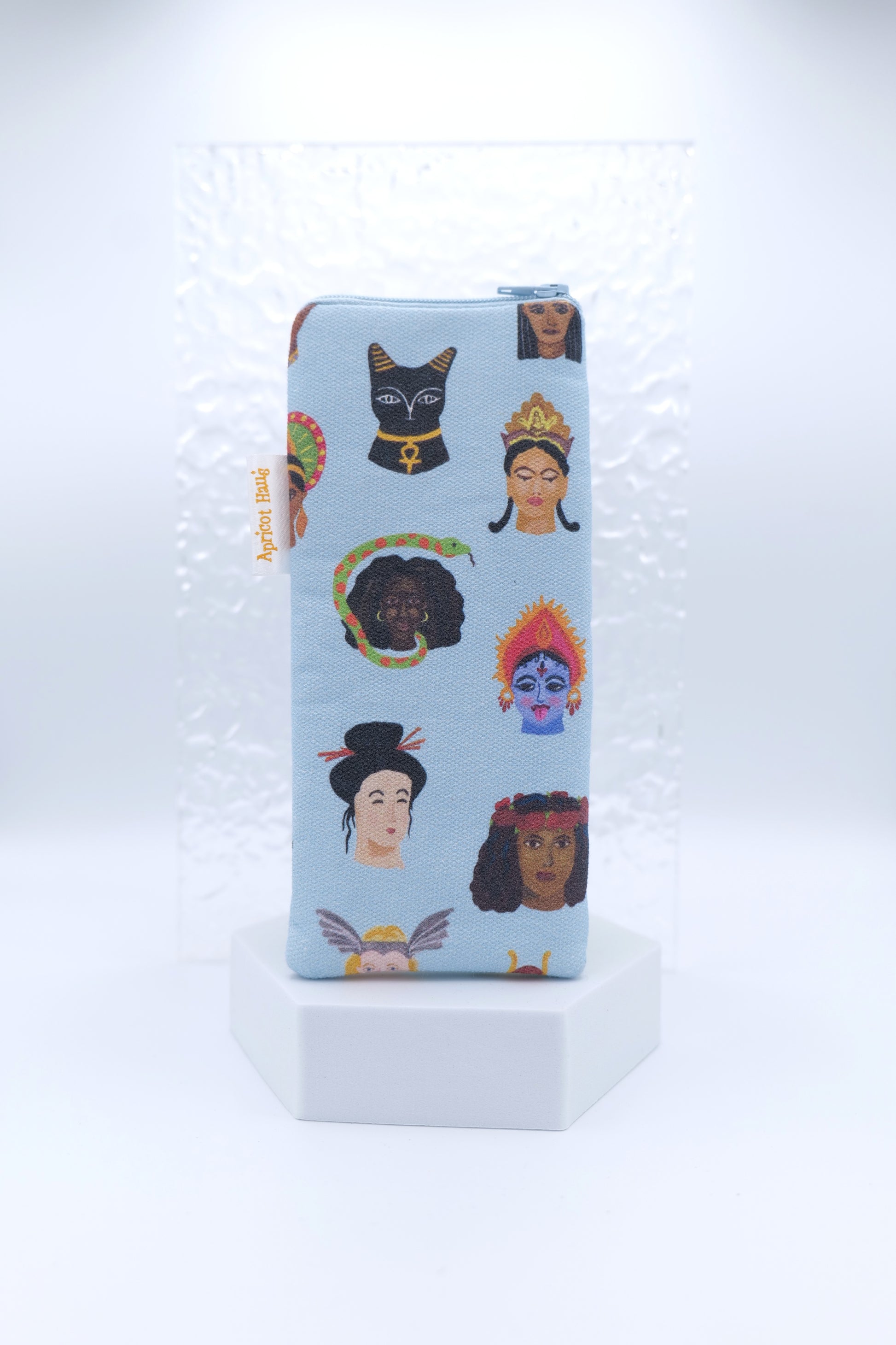 Glasses case featuring the Goddesses Around the World design with illustrated mythological female figures from diverse cultures on a pale blue background; made from cotton canvas with a zip-top closure, padded and lined to protect lenses, handmade in Melbourne and certified Australian Made; pattern placement may vary slightly due to the handmade nature of the product.