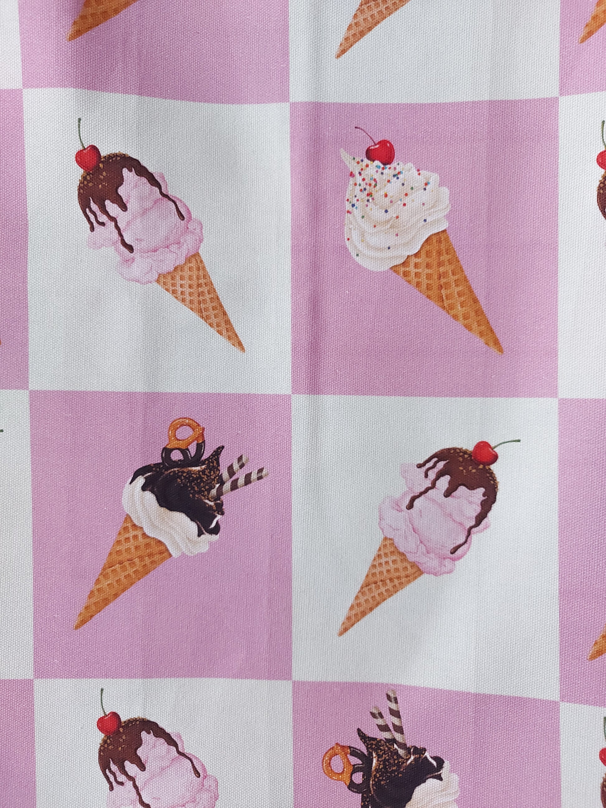 Close up photo of ice cream cones on pink and white grid background