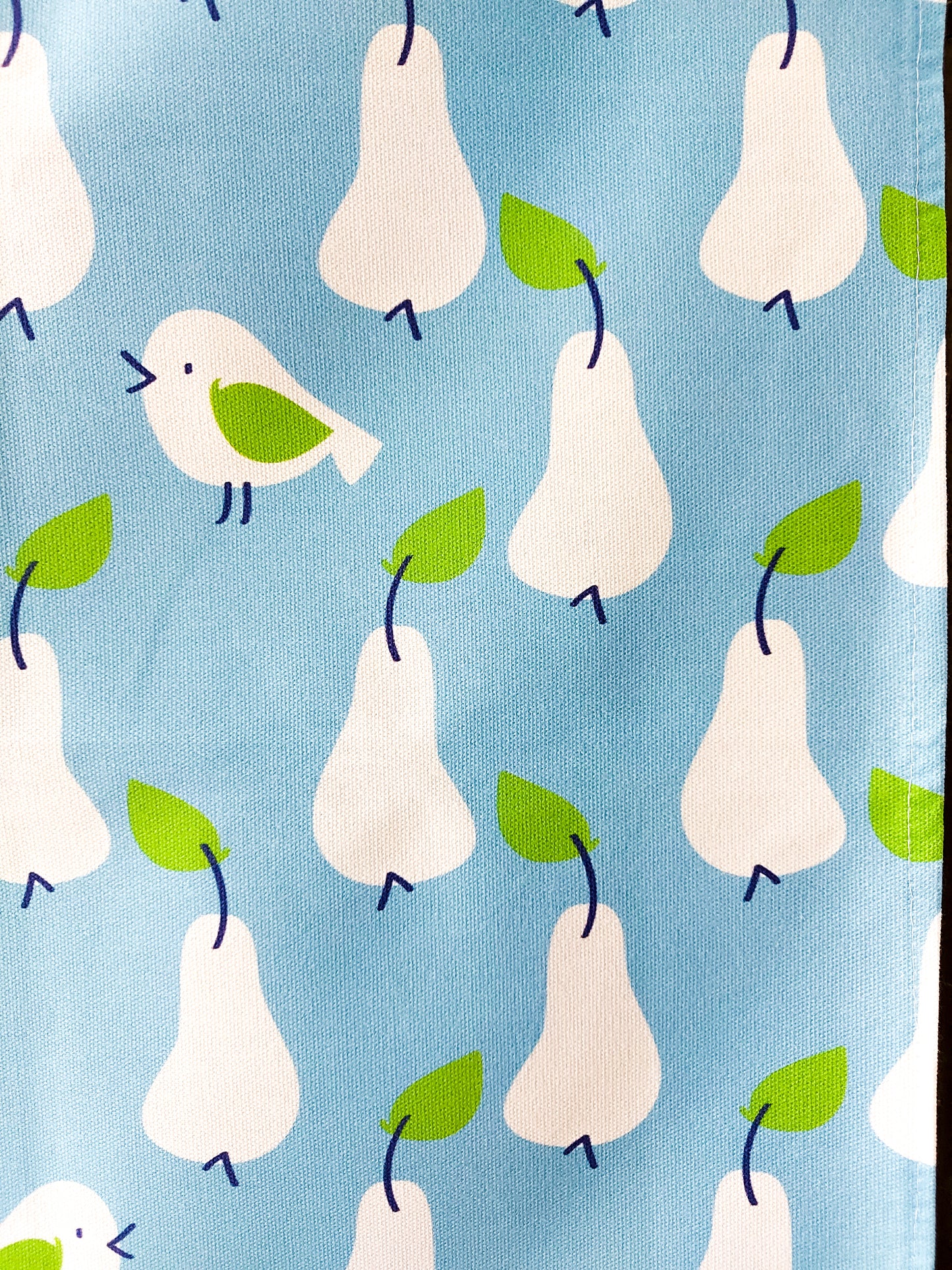 Close up photo of the Just Pears tea towel showing white pears and birds with green leaves on a light blue background