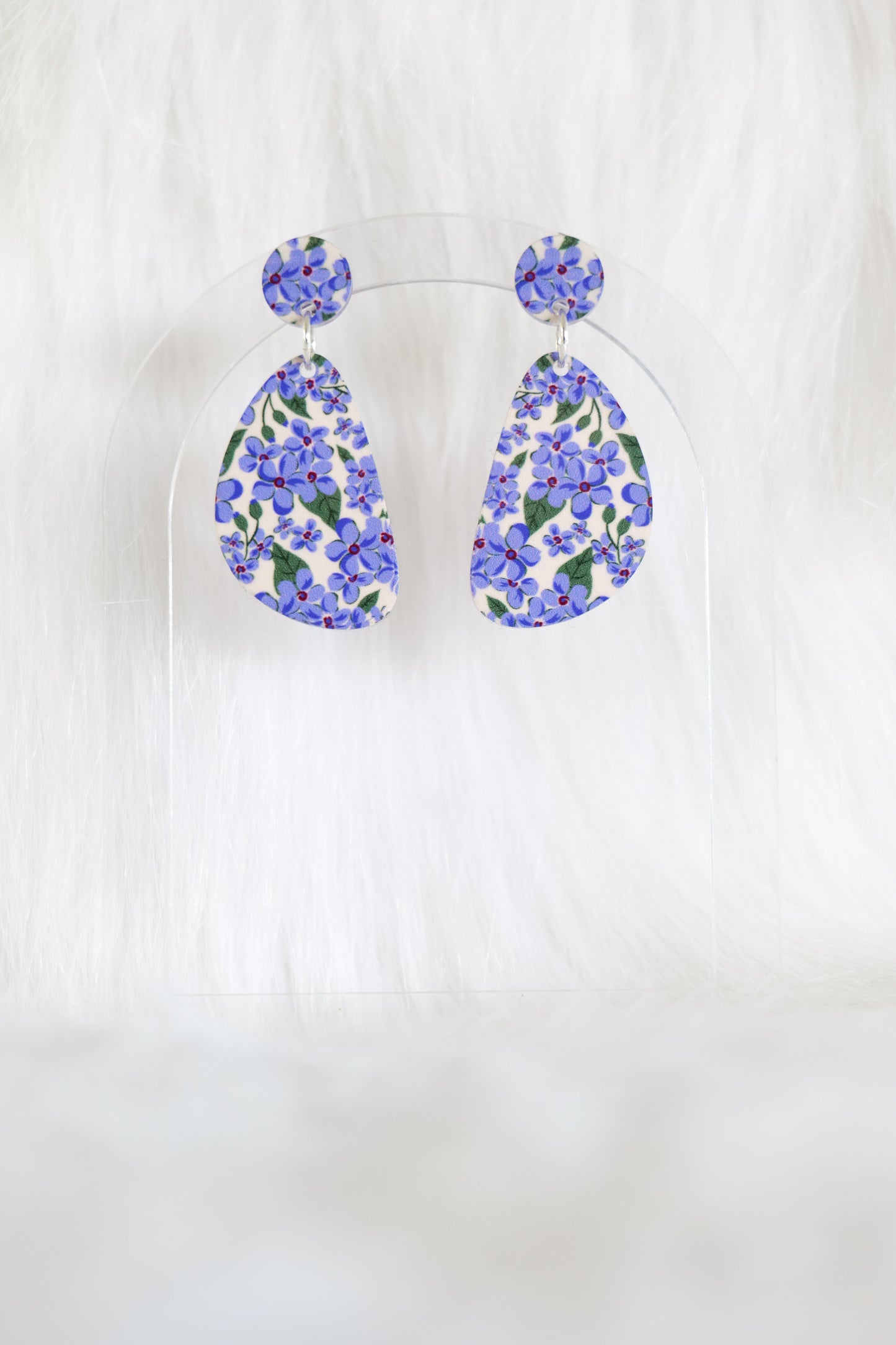 Pair of D-shaped earrings covered in small mauve flowers on a cream background, displayed against a white background; earrings are lightweight acrylic, have stainless steel posts and a large back