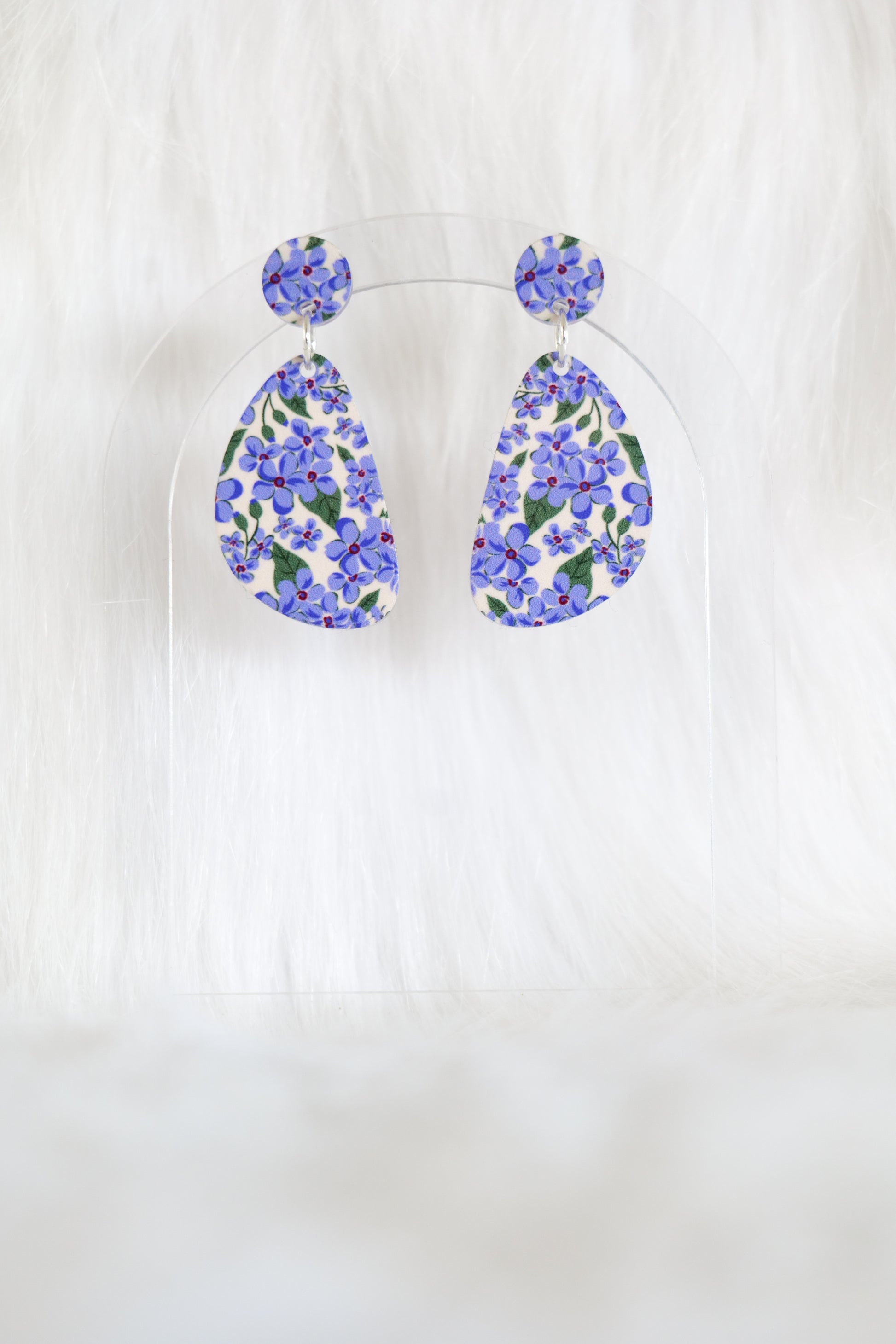 Pair of D-shaped earrings covered in small mauve flowers on a cream background, displayed against a white background; earrings are lightweight acrylic, have stainless steel posts and a large back
