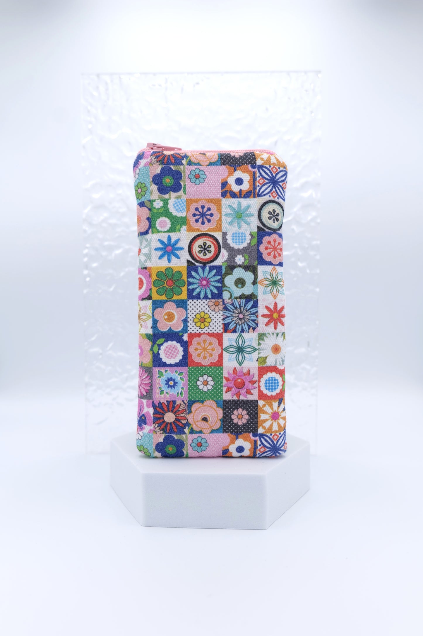 Glasses case with Les Fleurs design featuring a colourful patchwork of small square tiles, each with a small floral motif in pink, blue, green, orange, and purple; made from cotton canvas with zip top closure, padded and lined with soft cotton, handmade in Melbourne and certified Australian Made; pattern placement may vary slightly and individual items may have small quirks due to the handmade nature of the product.