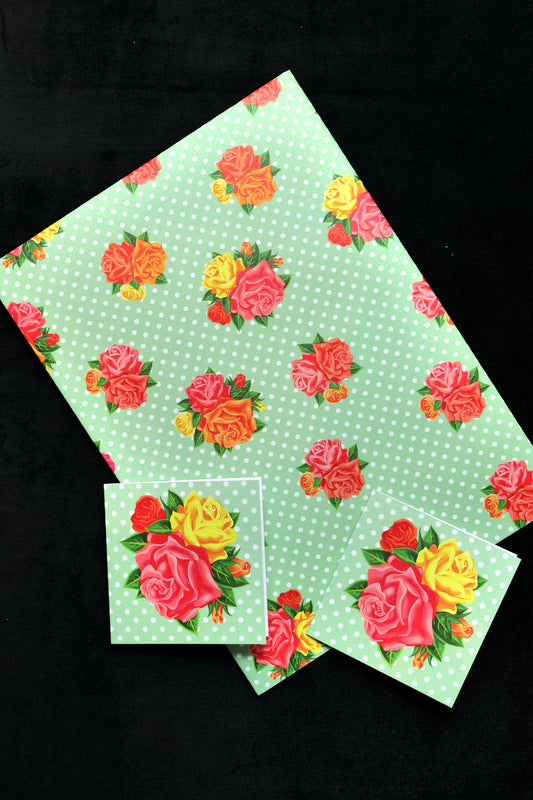 Photo showing folded gift wrap with two matching cards featuring a green polka-dot background with pink, orange and yellow roses; displayed against a black backdrop