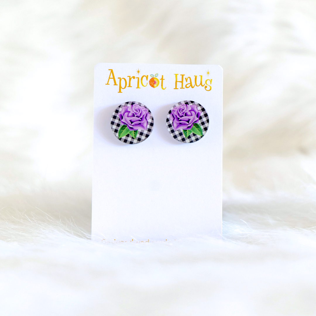 Pair of 2cm round acrylic stud earrings featuring a traditional style purple rose on a black and white check background; earrings have stainless steel posts and large accessible backs, displayed on an Apricot Haus earring card