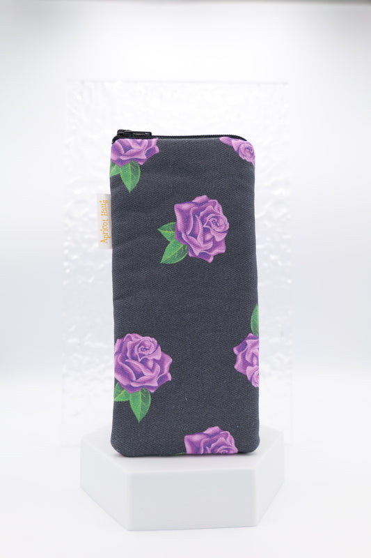 Glasses case featuring a Purple Roses design with violet rose clusters and green leaves on a dark charcoal background; made from cotton canvas with a zip-top closure, padded and lined to protect lenses, handmade in Melbourne and certified Australian Made; pattern placement may vary slightly due to the handmade nature of the product.
