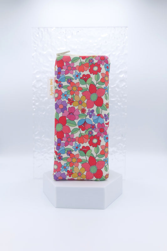 Glasses case featuring the Red Petals design with densely packed florals in red, pink, purple, yellow, green and blue on a cream background; made from cotton canvas with a zip-top closure, padded and lined to protect lenses, handmade in Melbourne and certified Australian Made; pattern placement may vary slightly due to the handmade nature of the product.
