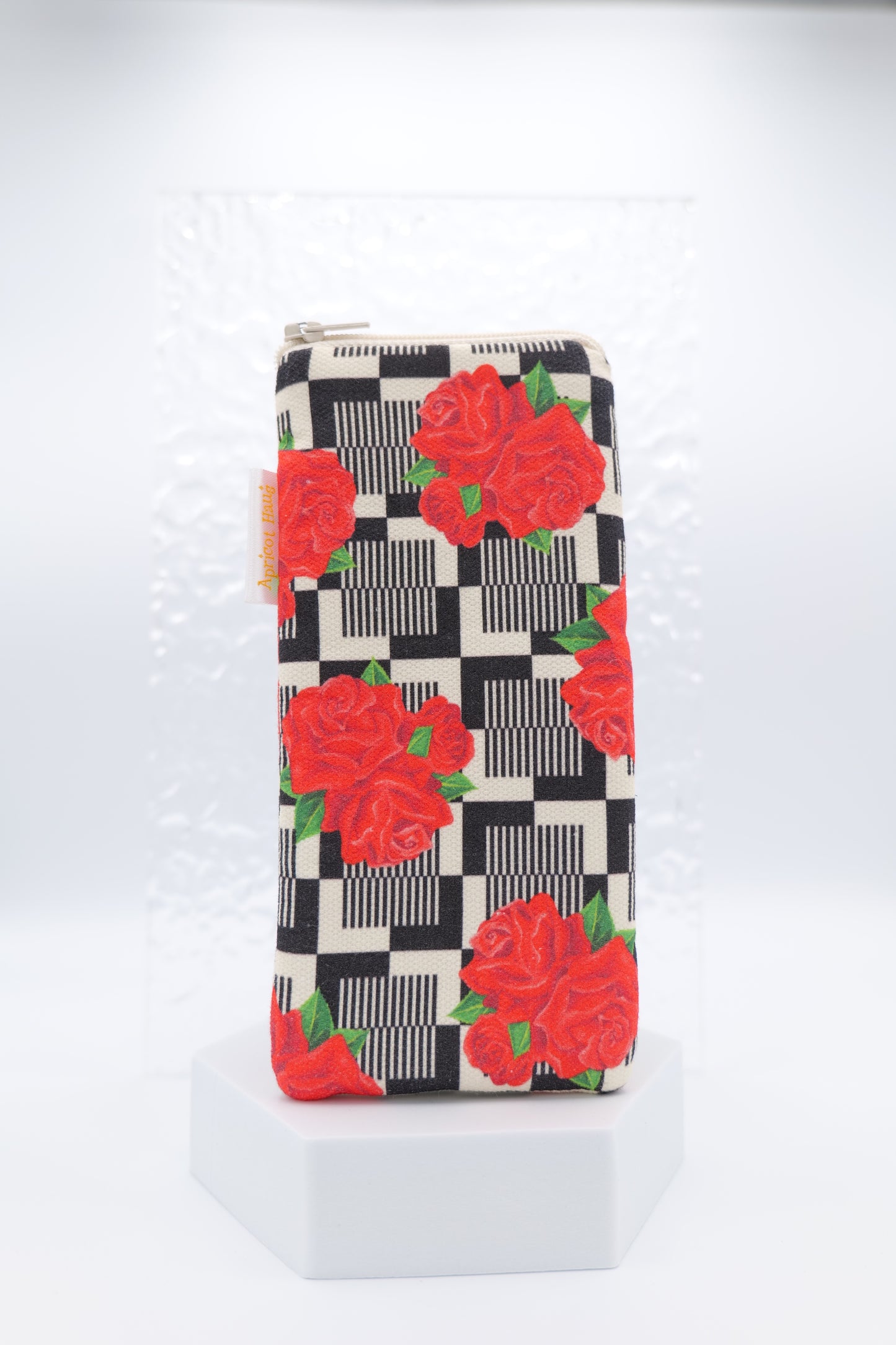 Glasses case featuring the Red Roses design with bold red rose clusters set against a retro-style black check background; made from cotton canvas with a zip-top closure, padded and lined to protect lenses, handmade in Melbourne and certified Australian Made; pattern placement may vary slightly due to the handmade nature of the product.
