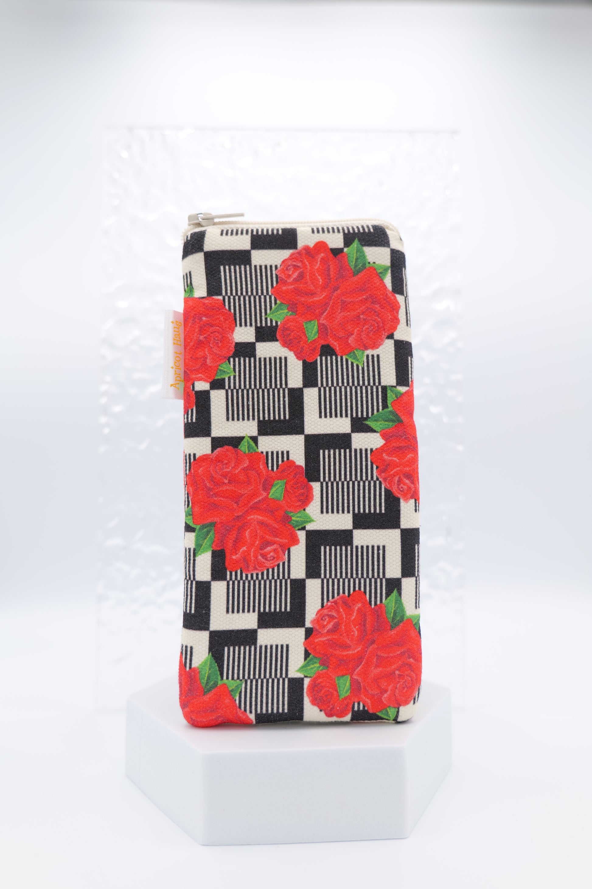 Glasses case featuring the Red Roses design with bold red rose clusters set against a retro-style black check background; made from cotton canvas with a zip-top closure, padded and lined to protect lenses, handmade in Melbourne and certified Australian Made; pattern placement may vary slightly due to the handmade nature of the product.