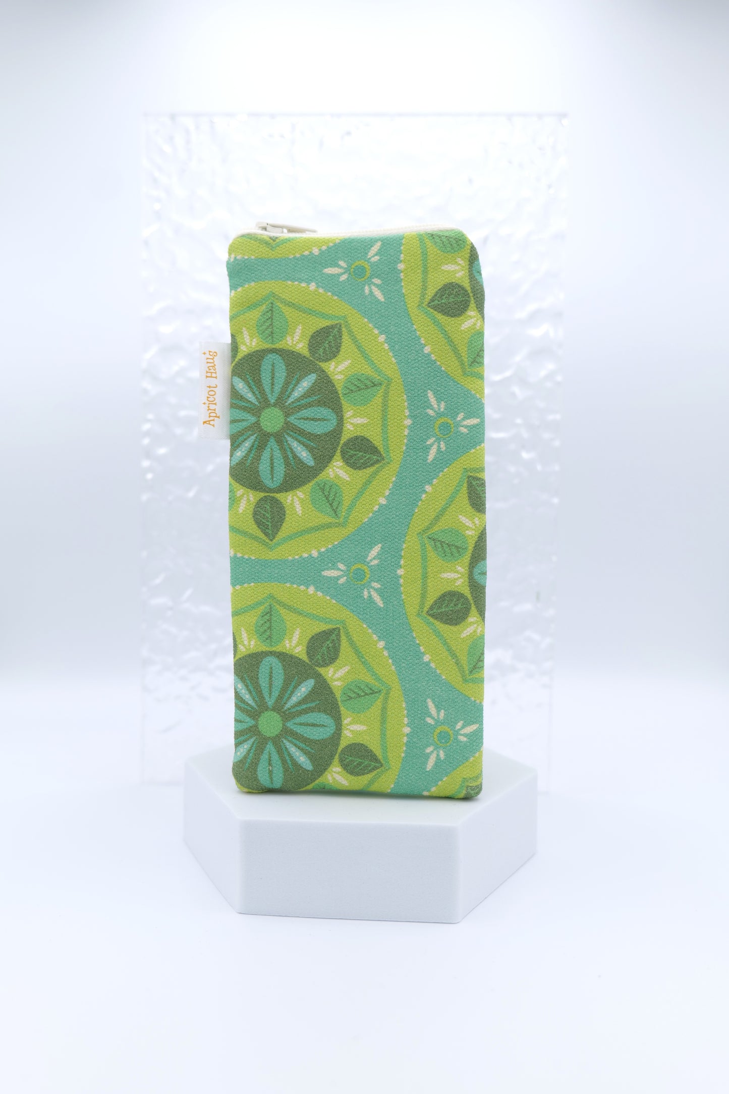 Glasses case featuring a Scandi Mandala design with circular floral motifs in green, teal and yellow on a teal background; made from cotton canvas with a zip-top closure, padded and lined to protect lenses, handmade in Melbourne and certified Australian Made; pattern placement may vary slightly due to the handmade nature of the product.