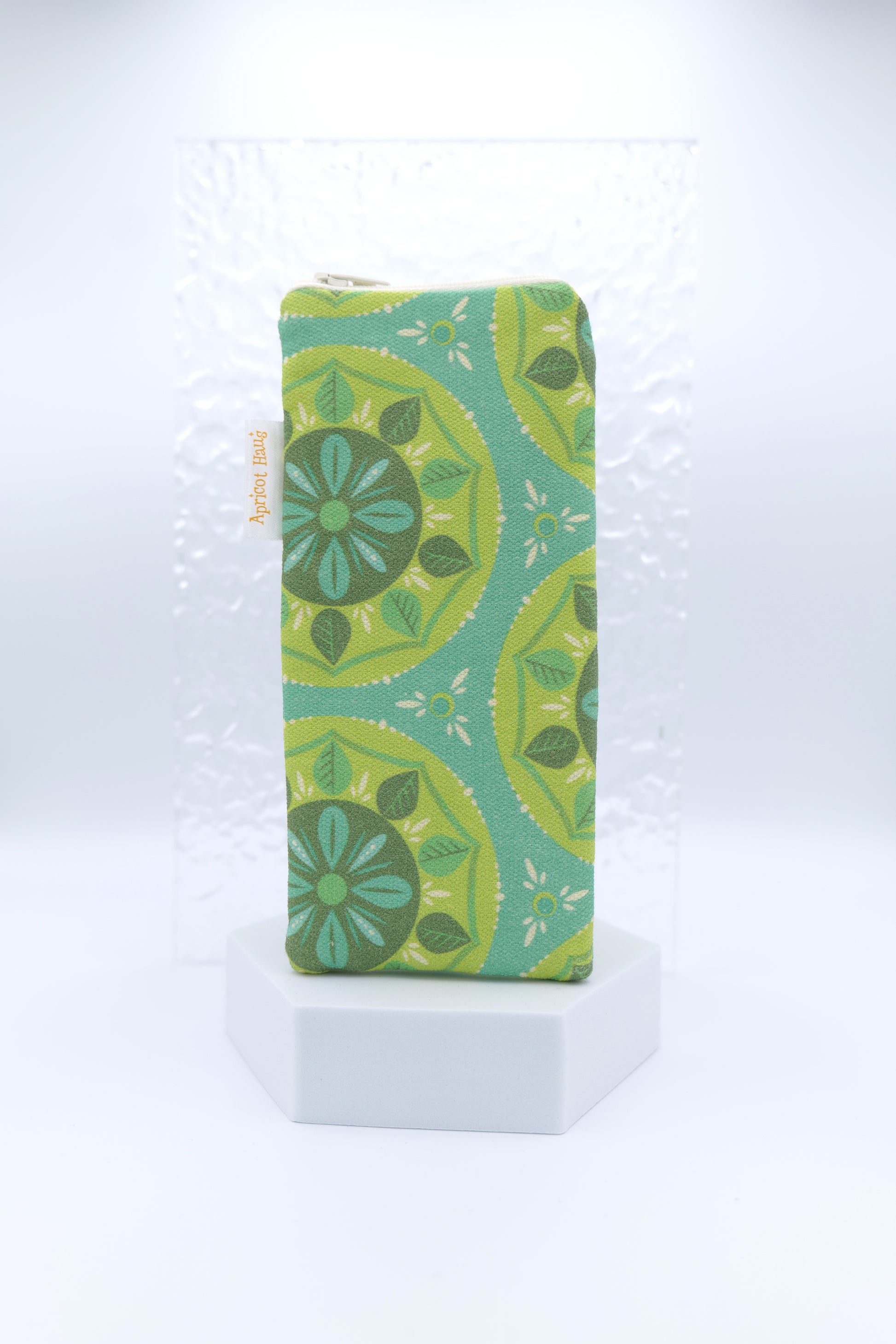 Glasses case featuring a Scandi Mandala design with circular floral motifs in green, teal and yellow on a teal background; made from cotton canvas with a zip-top closure, padded and lined to protect lenses, handmade in Melbourne and certified Australian Made; pattern placement may vary slightly due to the handmade nature of the product.