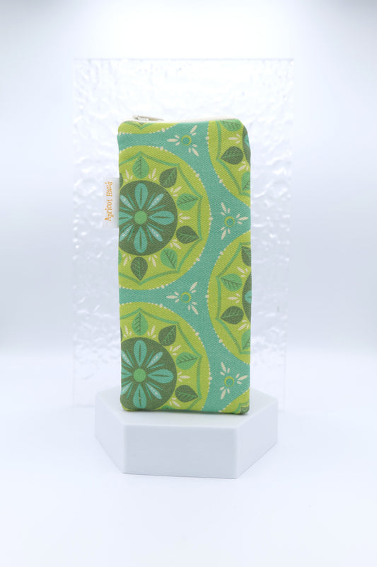 Glasses case featuring a Scandi Mandala design with circular floral motifs in green, teal and yellow on a teal background; made from cotton canvas with a zip-top closure, padded and lined to protect lenses, handmade in Melbourne and certified Australian Made; pattern placement may vary slightly due to the handmade nature of the product.