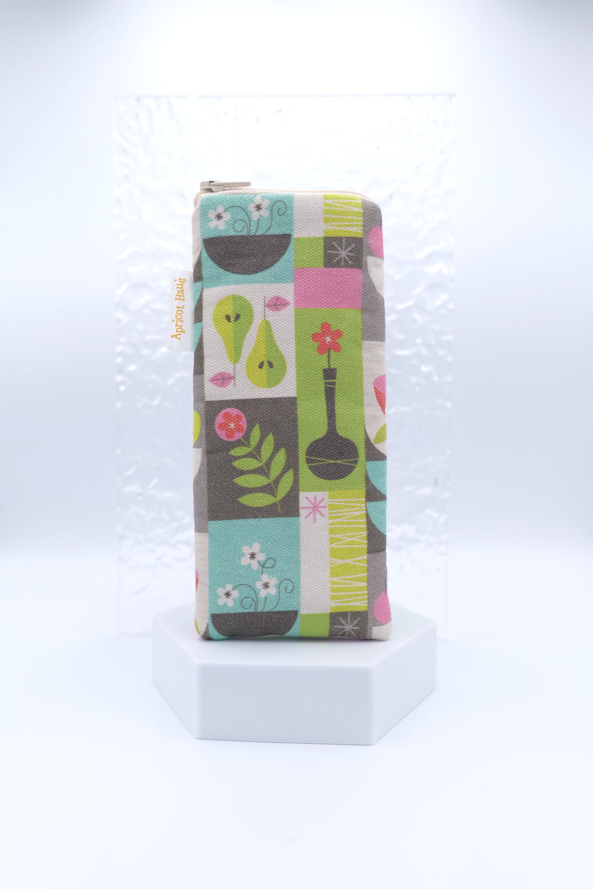 Glasses case featuring the Scandi Mod Patchwork design with stylised pears, flowers, leaves, and abstract shapes in green, pink, turquoise, grey and white on a soft grid layout; Scandinavian patchwork style with mid-century design elements; made from cotton canvas with a zip-top closure, padded and lined to protect lenses, handmade in Melbourne and certified Australian Made; pattern placement may vary slightly due to the handmade nature of the product.