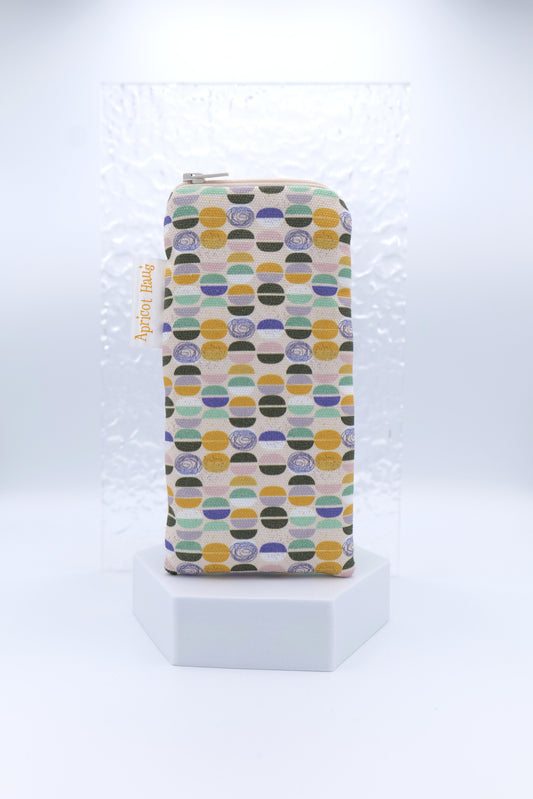 Glasses case featuring a Semicircles design with colourful circular and semicircular motifs in yellow, black, green, purple and blue on a soft background; made from cotton canvas with a zip-top closure, padded and lined to protect lenses, handmade in Melbourne and certified Australian Made; pattern placement may vary slightly due to the handmade nature of the product.