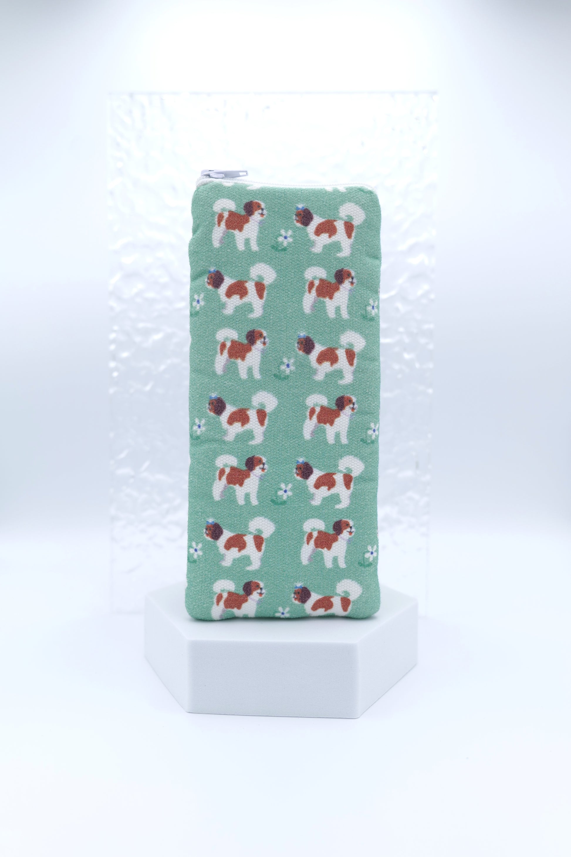 Glasses case featuring the Shih-Tzus design with hand-drawn white and brown dogs and scattered white flowers on a soft green background; made from cotton canvas with a zip-top closure, padded and lined to protect lenses, handmade in Melbourne and certified Australian Made; pattern placement may vary slightly due to the handmade nature of the product.
