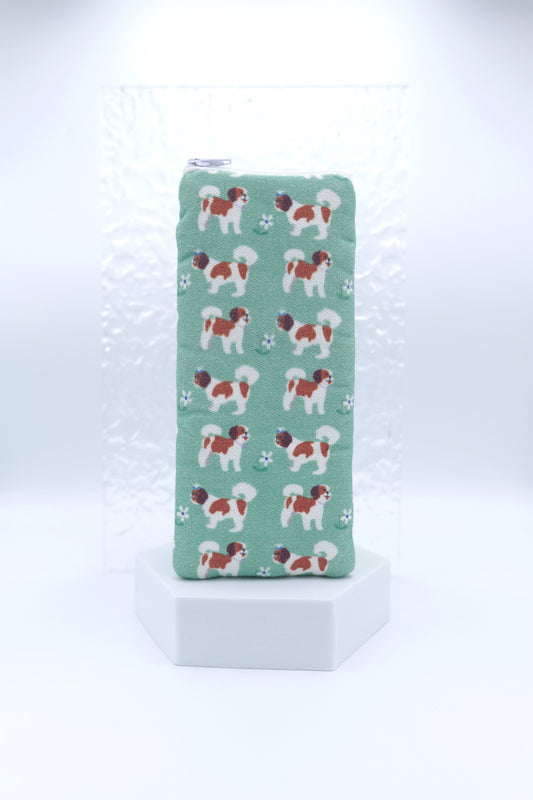 Glasses case featuring the Shih-Tzus design with hand-drawn white and brown dogs and scattered white flowers on a soft green background; made from cotton canvas with a zip-top closure, padded and lined to protect lenses, handmade in Melbourne and certified Australian Made; pattern placement may vary slightly due to the handmade nature of the product.
