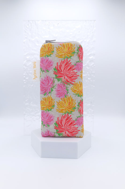Glasses case featuring a Sketch Flowers design with hand-drawn flowers in coral, pink, and yellow on a grey-beige background; made from cotton canvas with a zip-top closure, padded and lined to protect lenses, handmade in Melbourne and certified Australian Made; pattern placement may vary slightly due to the handmade nature of the product.