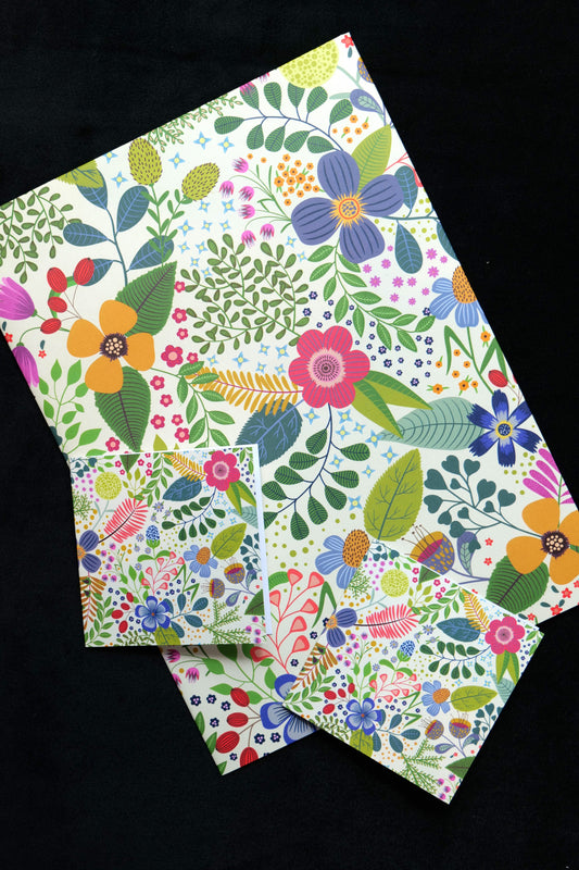A folded piece of gift wrap and two small gift cards featuring the bright Spring Garden design, displayed against a black background