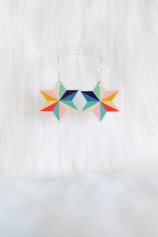 Pair of multicoloured acrylic star-shaped earrings with geometric segments in pink, red, yellow, green, blue and beige; on stainless steel hooks, displayed against a white background