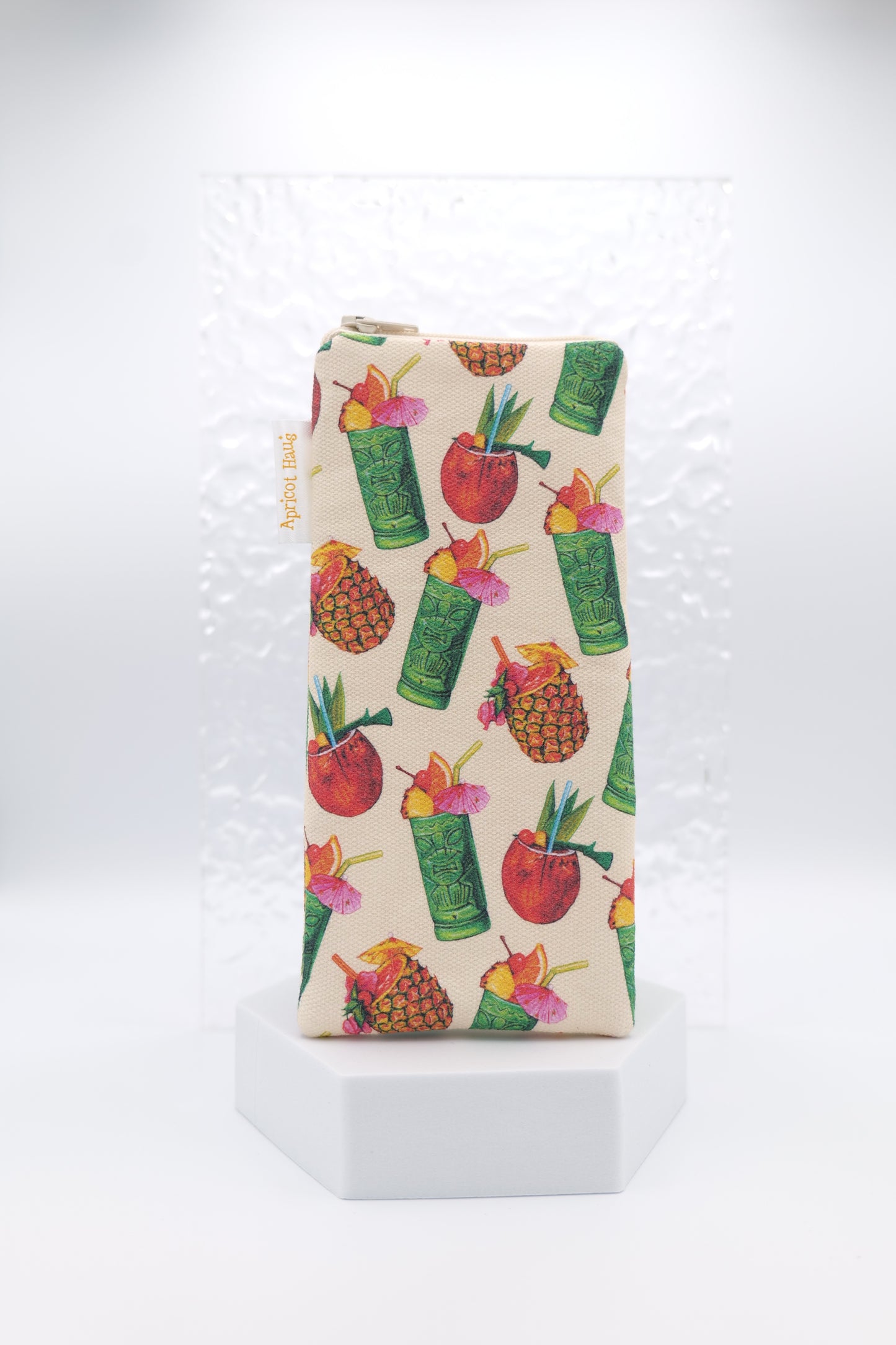 Glasses case featuring the Tiki Cocktail design with colourful illustrations of tiki mugs, pineapples, coconuts and tropical drinks on a cream background; made from cotton canvas with a zip-top closure, padded and lined to protect lenses, handmade in Melbourne and certified Australian Made; pattern placement may vary slightly due to the handmade nature of the product.