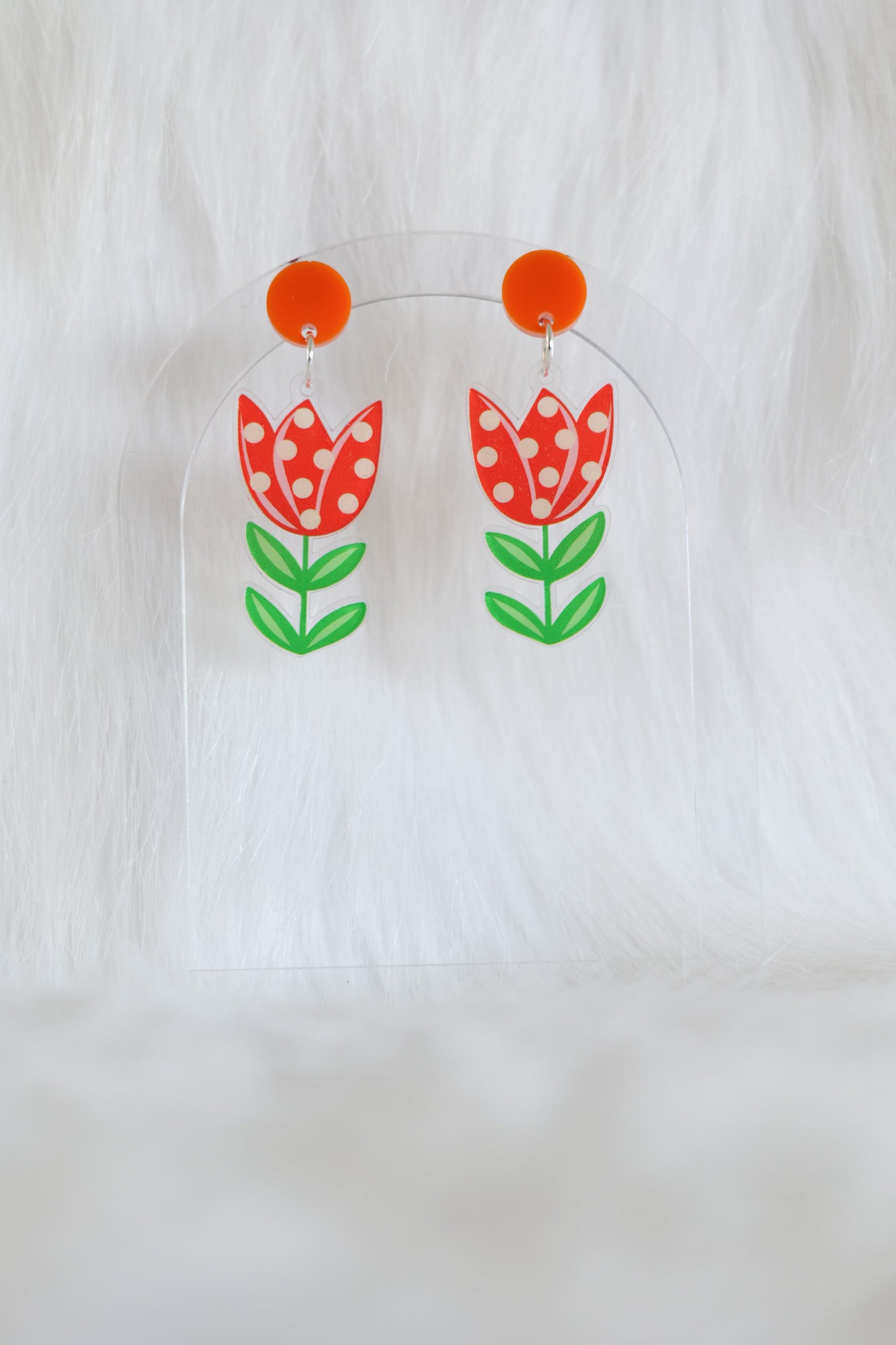Pair of acrylic earrings shaped like red tulips with white polka dots and green leaves attached to orange circular studs; lightweight with stainless steel posts and large backs, designed and made in Australia