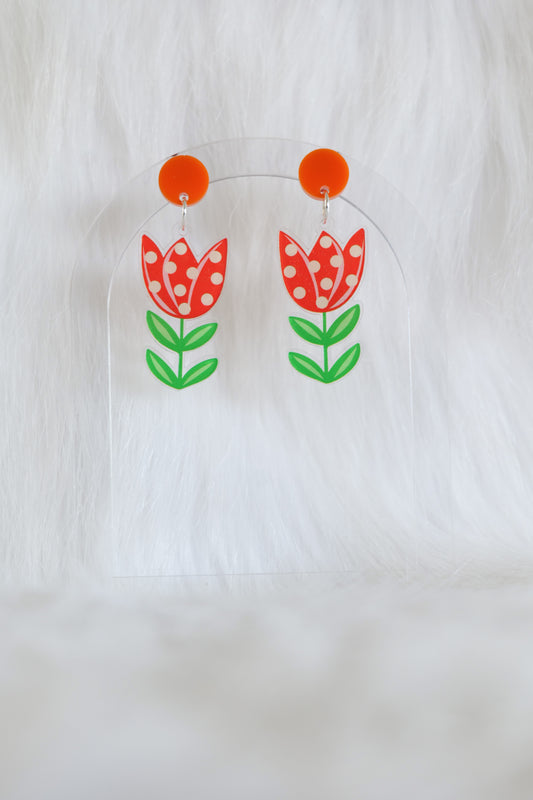 Pair of acrylic earrings shaped like red tulips with white polka dots and green leaves attached to orange circular studs; lightweight with stainless steel posts and large backs, designed and made in Australia